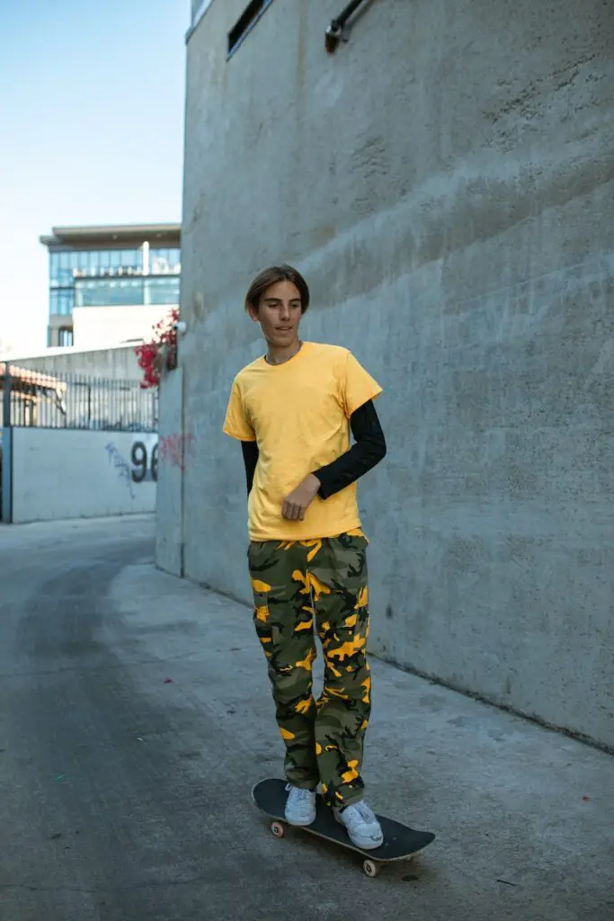 Man in Yellow Shirt Standing on a Skateboard, camouflage pants 