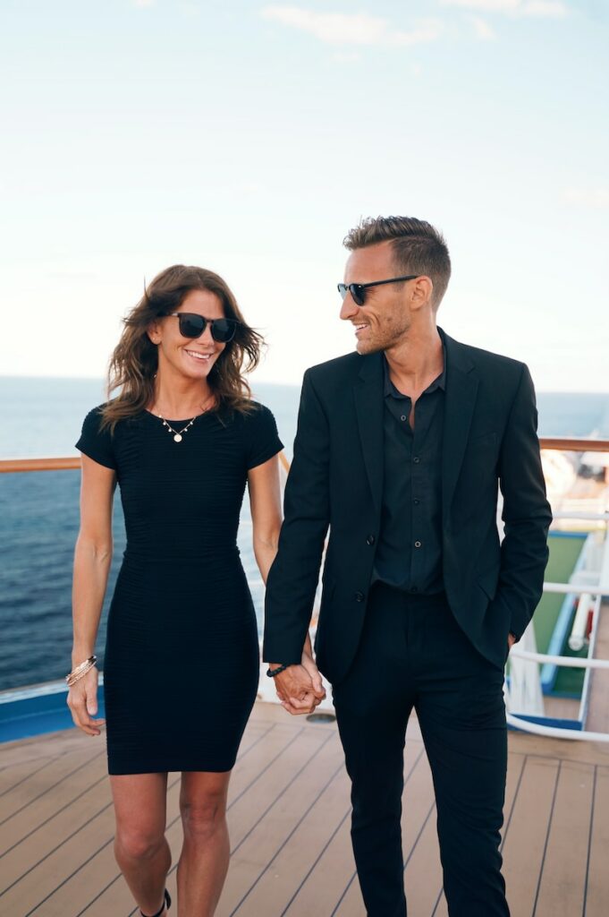 a man and woman wearing sunglasses and standing on a deck