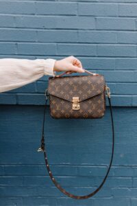 person holding brown leather sling bag, Louis Vuitton
