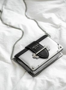 black leather sling bag on white textile, Prada bag